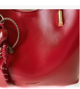 Dettaglio borsa a mano in pelle rossa cerata con ciondolo a cuore e metallo dorato