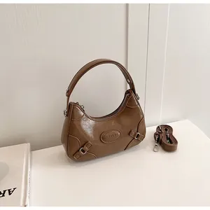 Detail of dark brown crescent handbag with embossed logo and adjustable shoulder strap