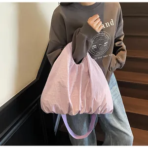 Detailed view of a light purple puffy tote bag worn on a shoulder in a casual setting