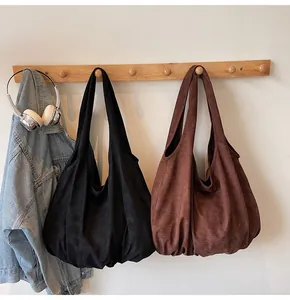 Detail of large suede tote bags in black and brown hanging in a casual interior setting