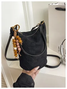 Detail der schwarzen Wildleder-Beuteltasche mit Steppnaht und bunter Holzperlen-Deko