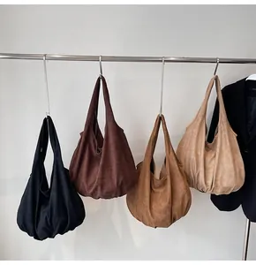 Macro view of four large suede tote bags in black, brown, caramel and beige