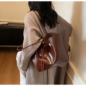Dettaglio della borsa tote in pelle marrone scuro con ciondolo intrecciato e logo