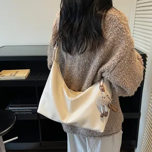 Minimalist beige semi-circle leather tote bag with a cute plush charm on shoulder