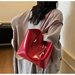 Borsa tote rossa in pelle cerata con ciondolo a cuore indossata con un cappotto