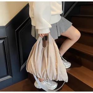 Detail of beige pleated canvas tote bag showing textured fabric and wide shoulder strap