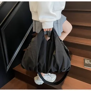 Close-up of a large black nylon tote bag showing its slouchy texture and wide shoulder strap