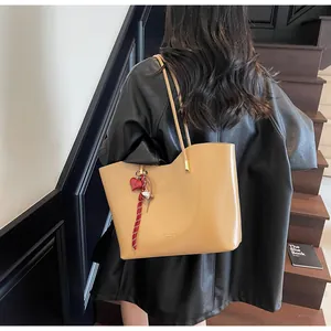 Dettaglio della borsa tote in ecopelle kaki con manici sottili e ciondolo a cuore