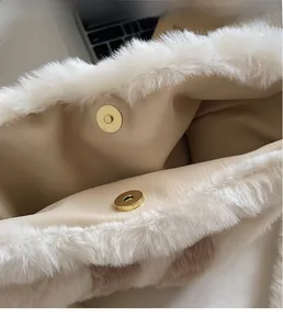 Detail of the golden magnetic metal clasp on the plush white faux fur tote bag