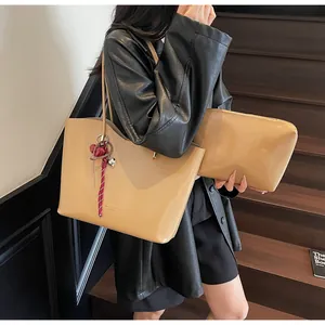 Dettaglio del set borsa tote e pochette in pelle cerata beige con ciondolo a cuore