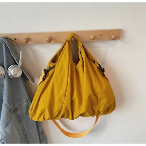 Close-up of mustard yellow crinkled tote bag with black hooks on a wooden hanger