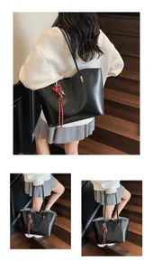 Dettaglio di una borsa tote in pelle cerata nera con ciondolo a cuore su una scala in legno