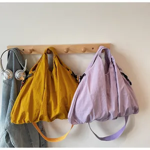 Detail of canvas tote bags in ginger and lilac with drawstrings on a wooden rack