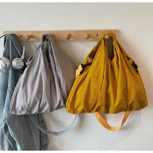 Detail of adjustable buckles on gray and yellow oversized slouchy nylon tote bags