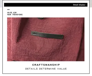 Detail eines weinroten Nylon-Rucksacks mit strukturiertem Stoff und schwarzem Lederbesatz