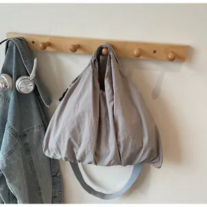 Detail of taupe nylon tote bag hanging on a wooden rack with headphones and denim jacket