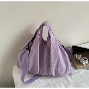Detail of light purple nylon shoulder bag showing wide strap and plastic buckle
