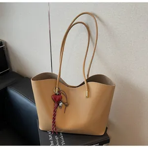 Dettaglio della borsa tote kaki in pelle cerata con bordo ondulato e ciondolo a cuore