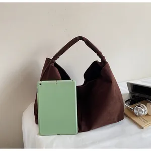Detail of a large brown suede tote bag holding a tablet to show its spacious interior