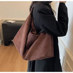 Detail of a large brown suede shoulder bag with a matte texture and minimalist design