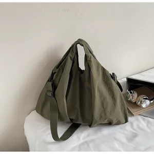 Detail of army green nylon tote bag with pleated texture and adjustable shoulder strap