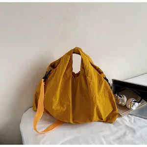 Close-up of yellow canvas tote bag featuring adjustable black side strap detail