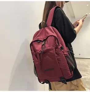 Detailansicht eines weinroten Nylon-Rucksacks mit mehreren Reißverschlussfächern