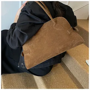 Detail einer braunen Wildleder-Tote-Bag mit seitlichen Schnallenriemen am Model