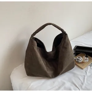 Detail of suede hobo bag knot strap and rich brown texture in lifestyle setting