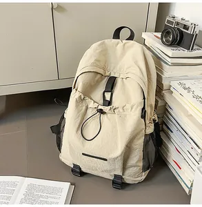 Detail eines cremefarbenen Nylon-Rucksacks mit Kordelzugtasche und schwarzen Netztaschen