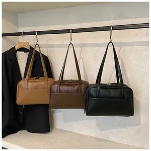 Drei minimalistische Kunstledertaschen in Schwarz, Braun und Hellbraun am Metallständer
