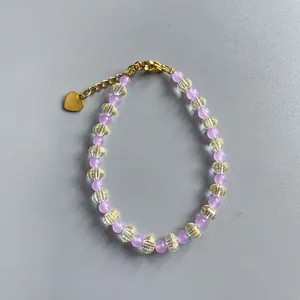 Détail du bracelet en perles violettes avec cristaux et un pendentif coeur doré