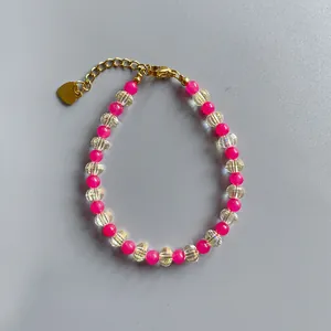 Détail du bracelet bohème en perles avec pierres roses, fermoir doré et pendentif cœur