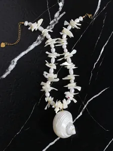 Detail van een schelpenketting met grote conch-hanger en natuurlijke zoetwaterparels