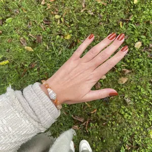 Dettaglio di un bracciale di perle in pietra naturale arancione con una conchiglia