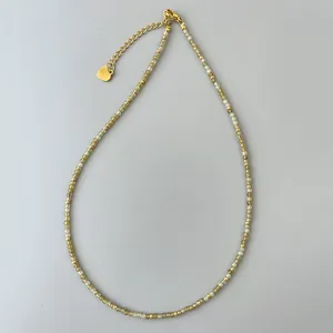 Dettaglio collana con perline di cristallo verde 2mm con ciondolo a cuore dorato e catena