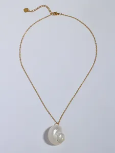 Detail van gouden ketting met een parelmoeren schelphanger en hartvormige bedel