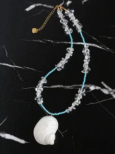 Detail van een blauwe kralenketting met een witte schelphanger en gouden sluiting