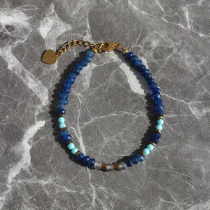 Blue natural stone beaded bracelet with turquoise accents and gold heart charm on marble