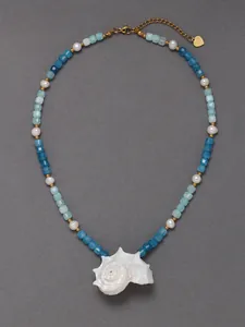 Detail van schelphanger ketting met blauwe stenen en witte parels op grijze achtergrond