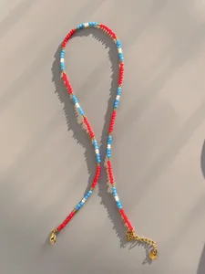 Detail of colorful beaded necklace with 18k gold plated lobster clasp and logo tag