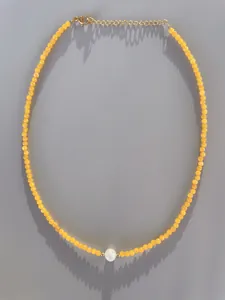 Detail of yellow beaded necklace with central pearl and 18k gold plated lobster clasp