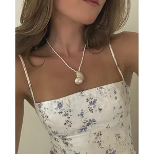 Minimalistische zoetwaterparelketting met natuurlijke schelphanger op een model