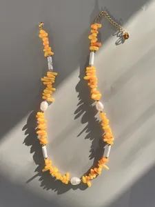 Detailed shot of handmade beaded necklace with natural stones, pearls and gold extension chain