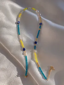 Macro shot of colorful beads and freshwater pearls on gold-plated stainless steel chain