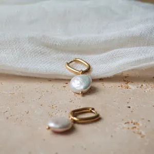 Boucles d'oreilles en acier titane avec perles baroques naturelles sur fond de pierre