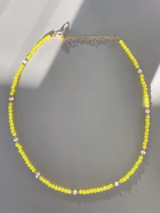 Macro detail of handmade necklace with yellow beads, white pearls, and 18k gold lobster clasp