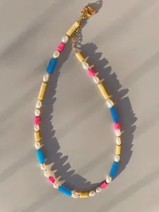 Macro view of multi-colored natural stone and baroque pearl beaded necklace with gold clasp