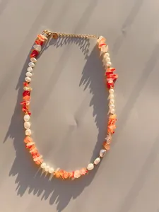 Dettaglio della collana con pietre arancioni, perle e catena regolabile dorata