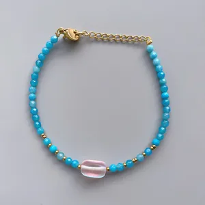 Detailed macro view of beaded bracelet with blue crystals and pink stone on grey background